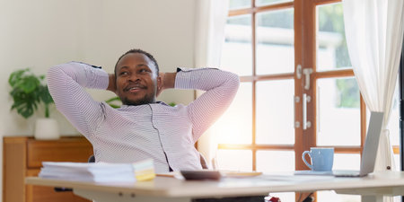 Smiling American African business person relaxing after analysis and research at home officeの写真素材
