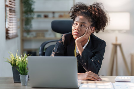 Tired American African business woman in stress works with many paperwork document. migraine attack. Freelance, work from homeの写真素材