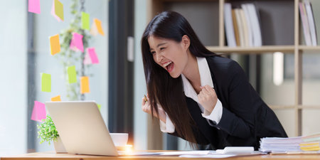Asian Businessperson using laptop and celebrating victory and success, have good news, job celebrating achievement.の写真素材