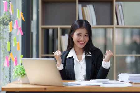 Asian Businessperson using laptop and celebrating victory and success, have good news, job celebrating achievement.の写真素材