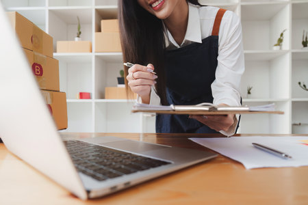 Small businesses SME owners female entrepreneurs check online orders to prepare to pack the boxes,...