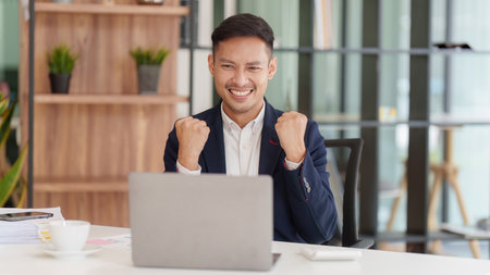Asian Businessperson using laptop and celebrating victory and success, have good news, job celebrating achievement.の写真素材