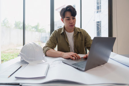 Architect or Engineer working with blueprints for architectural plan, engineer sketching a construction project, green energy conceptの写真素材