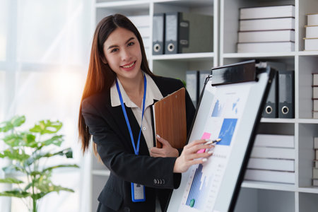 Smiling Asian Business person makes financial report and studies annual figures, analyzes profits. Accountant checks status of financialの写真素材