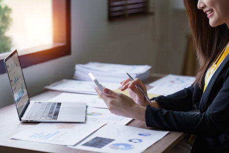 Asian Business person makes analysis and research financial report at office, analyzes profits. Accountant checks status of financialの写真素材