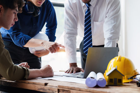 Architect and Engineer working with blueprints for architectural plan, engineer sketching a construction project, green energy conceptの写真素材