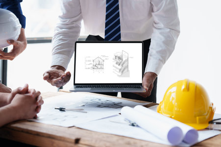 Architect and Engineer working with blueprints for architectural plan, engineer sketching a construction project, green energy conceptの写真素材