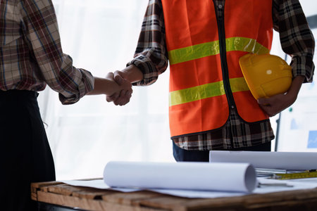 Architect and Engineer working with blueprints for architectural plan, engineer sketching a construction project, green energy conceptの写真素材