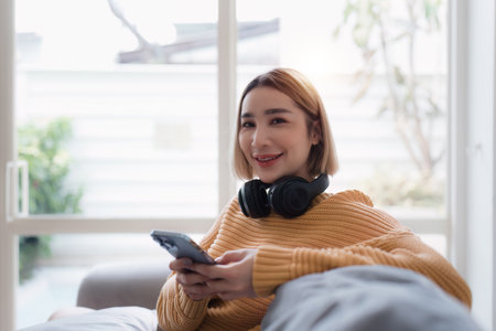 Attractive Asian woman resting comfortable living room and using mobile phone, Relax, Sofa,...