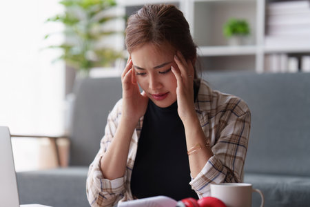 Stressed woman sits on sofa at home, studying and analyze house bills and submitting tax forms.の写真素材
