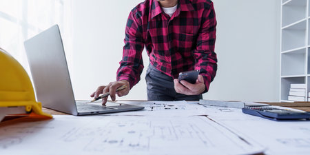 Architect and Engineer working with blueprints for architectural plan, engineer sketching a...