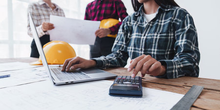 Architect and Engineer working with blueprints for architectural plan, engineer sketching a...
