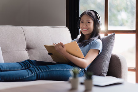 Online education, e-learning. Asian woman in stylish casual clothes, studying using a laptop,...