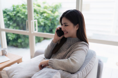 Attractive Asian woman resting comfortable living room and using mobile phone, Relax, Sofa, Lifestyleの写真素材