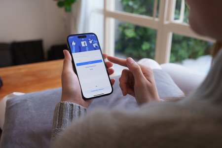CHIANG MAI ,THAILAND - APR 21, 2023 : Woman hand using iPhone 14 with facebook application by Metaverse. American digital company, owner of Facebook, Instagram, Oculus VRのeditorial素材