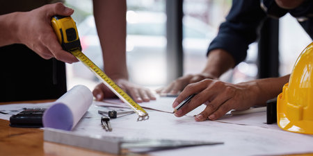 Architect and Engineer working with blueprints for architectural plan, engineer sketching a construction project, green energy conceptの写真素材