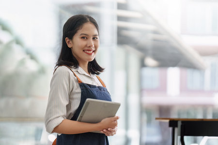Asian cafe owner or barista standing with smiling at cafe. woman small business owner in food and...