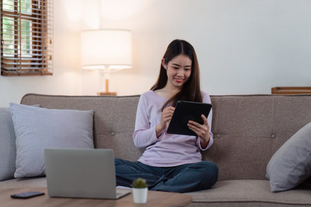 Attractive Asian woman resting comfortable living room and using digital tablet, Relax, Sofa, Lifestyleの写真素材