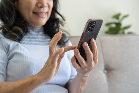 Elderly asian women using social media and living room. Video streaming, happiness and conversation at a house with old people togetherの写真素材
