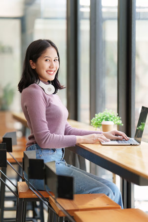 Portrait of young woman using laptop at cafe, business person working on laptop computer at a coffee shopの写真素材