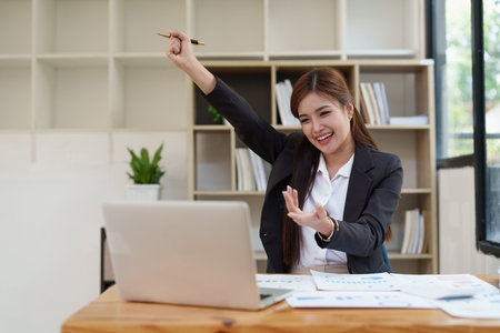 Asian Businessperson using laptop and celebrating victory and success, have good news, job celebrating achievement.の写真素材