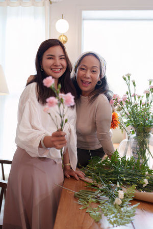 Startup, small business, flower shop. Young and older woman florist putting a flower on a vase