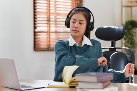Online education, e-learning. Asian woman relaxing after studying using a laptop, listening to...
