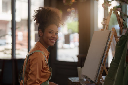 Beautiful american african artist woman painting in art studio at the university classroomの写真素材
