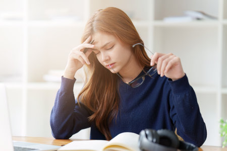 Sad teenager studying preparing for exam test in the university library. Depressed young woman student. Back to School conceptの写真素材