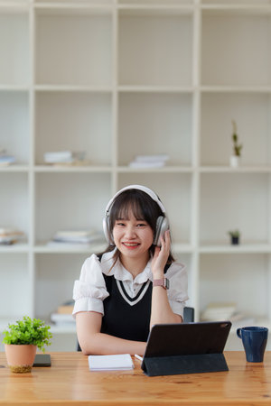 Online education, e-learning. Asian woman in stylish casual clothes, studying using a laptop,...