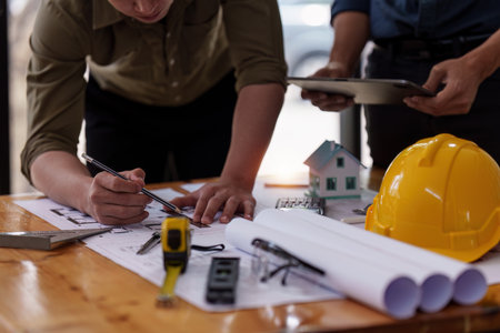 Architect and Engineer working with blueprints for architectural plan, engineer sketching a...