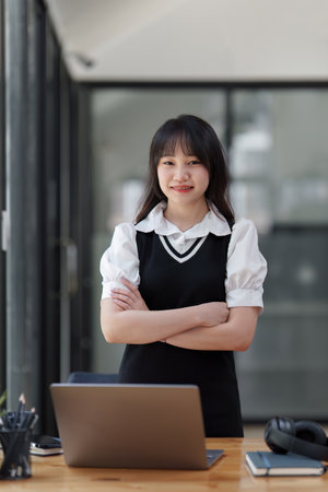 Online education, e-learning. Asian woman in stylish casual clothes, studying using a laptop, listening to online lecture, taking notes, online study at homeの写真素材