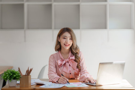 Smiling Asian Accountant person analyze financial report and studies annual figures, analyzes profitsの写真素材