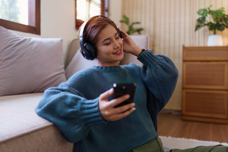 A Asian Womans Leisure at Home on a Cozy Sofa and listen to musicの写真素材