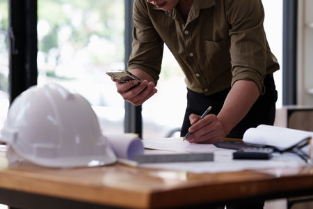 Architect working with blueprints for architectural plan, engineer sketching a construction project, green energy conceptの写真素材