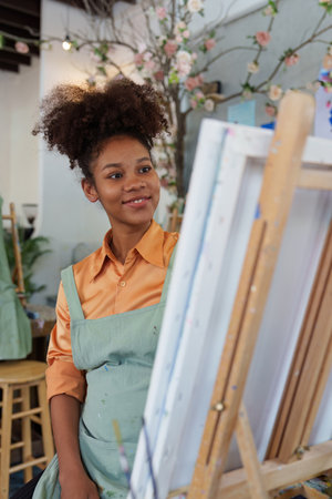 Beautiful american african artist woman painting in art studio at the university classroomの写真素材