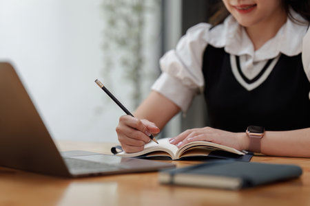 Online education, e-learning. Asian woman in stylish casual clothes, studying using a laptop,...