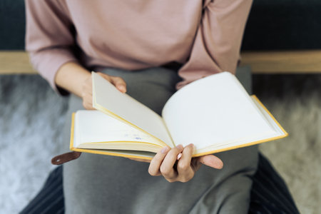 Closeup hand open book for reading in living roomの写真素材