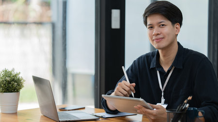 young Asian businessman using a digital tablet at a table in the officeの写真素材