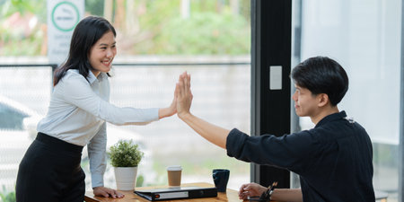 business colleagues looking at laptop and celebrating success at office