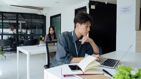 Tired stressed office worker sitting at desk and thinking, he is rubbing his eyes and feeling exhaustedの写真素材