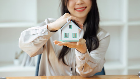 Real estate broker agent presenting and consult to customer to decision making sign insurance form agreement, home model, concerning mortgage loan offer for and house insurance.の写真素材