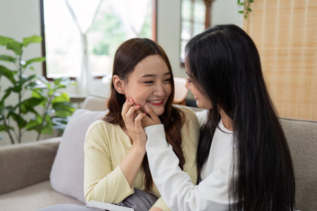 Loving LGBTQIA lesbian gay couple laughing together in Livingroom. Asian LGBTQIA lesbian gay couple laughed happy together while sitting on the sofa. Homosexual-LGBTQ concept.の写真素材
