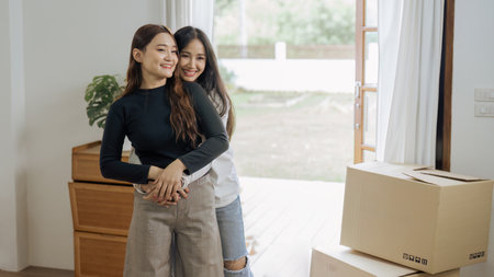 Young woman couple smiling happy and back hug after moving box at new homeの写真素材
