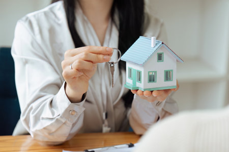 Real estate broker agent presenting and consult to customer to decision making sign insurance form agreement, home model, concerning mortgage loan offer for and house insurance.の写真素材