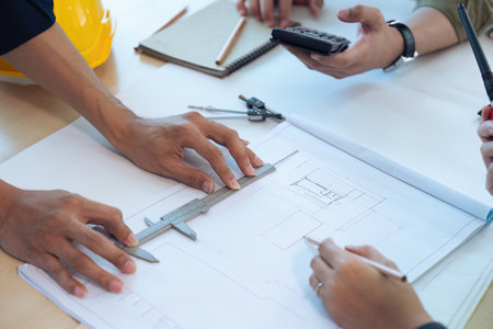 Close up of civil male engineer asian working on blueprint architectural project at construction site at desk in officeの写真素材
