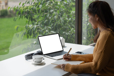 Young woman using laptop at home, student girl using laptop computer with blank white empty screen...