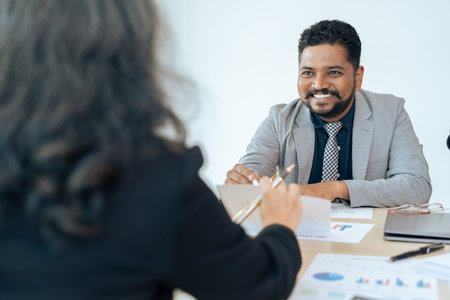 Smiling mature middle aged businessman discussing investing with supervisor businesswoman at meeting roomの写真素材