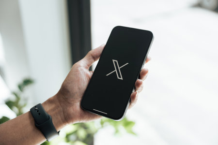 CHIANG MAI, THAILAND - July 28, 2023: Man holding a Apple iPhone with Twitter logo on the screen. Twitter is a social media online service for microblogging and networking communication.のeditorial素材