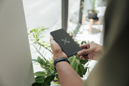 CHIANG MAI, THAILAND - July 28, 2023: Man holding a Apple iPhone with Twitter logo on the screen. Twitter is a social media online service for microblogging and networking communication.のeditorial素材